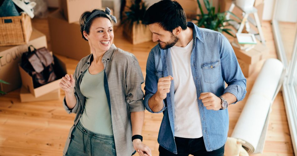 Happy couple having fun and dancing while moving into a new home.