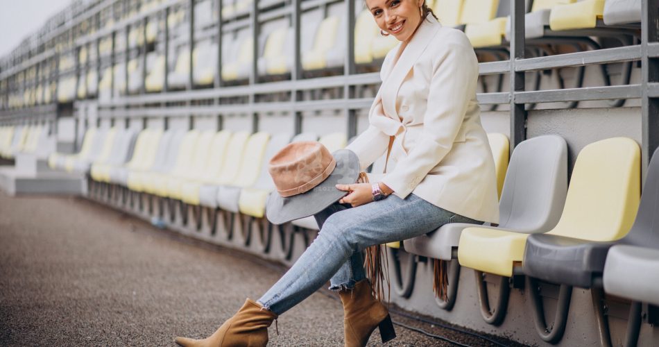 Young woman in white jacket holding hat